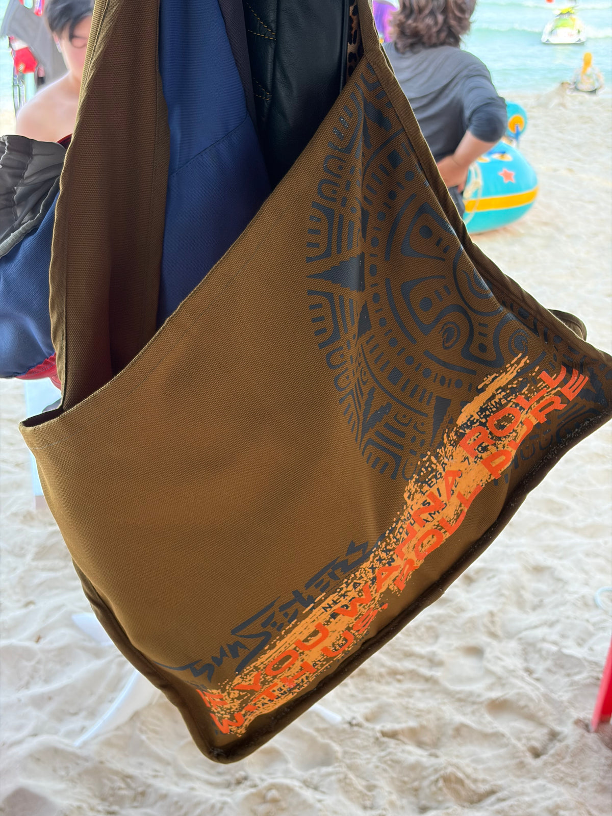 Sunseekers oversized khaki messenger bag with signature artwork and orange detailing